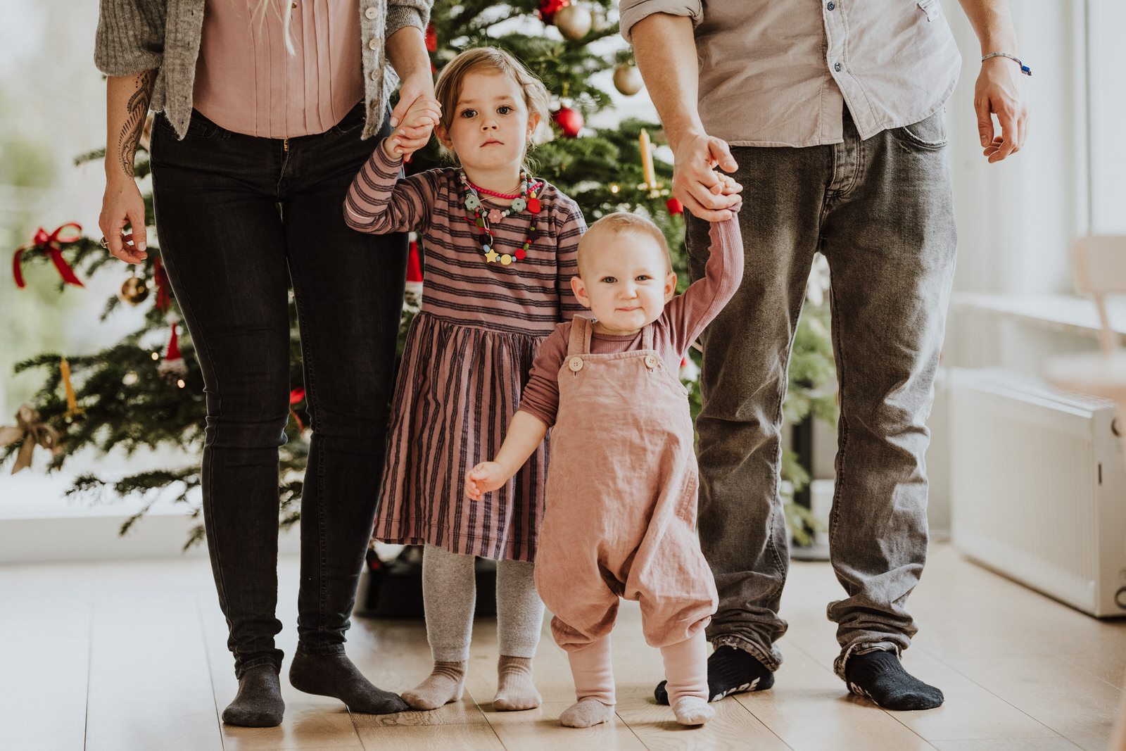Ein Mann und eine Frau stehen mit zwei Kindern vor dem Weihnachtsbaum.