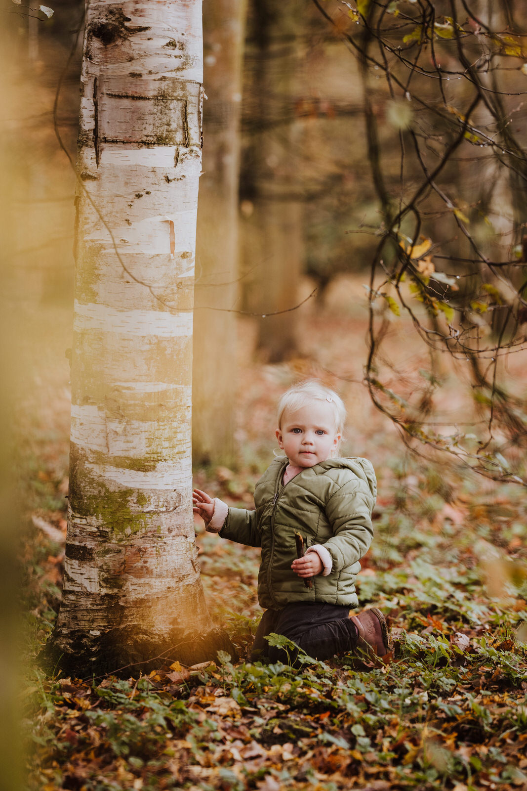 Ein kleines Kind sitzt vor einem Baum.