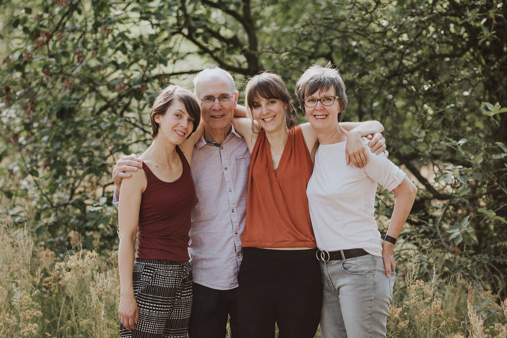 Eine Gruppe von Menschen die im Wald stehen und für ein Familienfoto posieren.