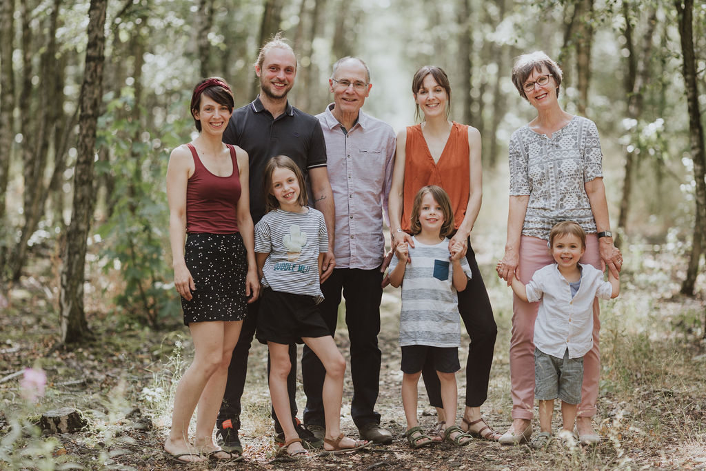 Eine Gruppe von Menschen die im Wald stehen und für ein Familienfoto posieren.