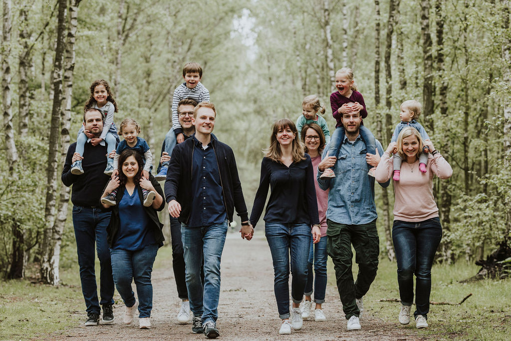 Eine Gruppe von Menschen die im Wald spazieren und für ein Familienfoto posieren.