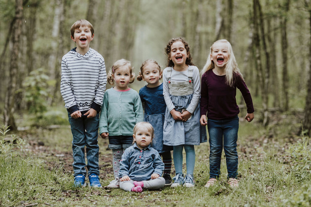 Eine Gruppe von Kindern die im Wald steht und für ein Familienfoto posiert.