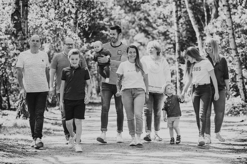 Eine Gruppe von Menschen die im Wald spazieren und für ein Familienfoto posieren.