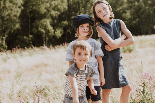 Drei Kinder stehen auf einer Wiese.