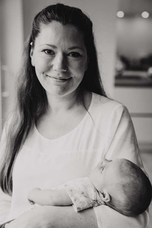 Ein schwarz-weiß Fotos von einer Frau die ein kleines Baby auf dem Arm hält.