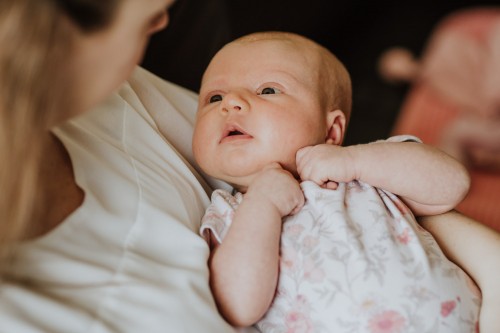 Ein kleines Baby schaut zu einer Frau.