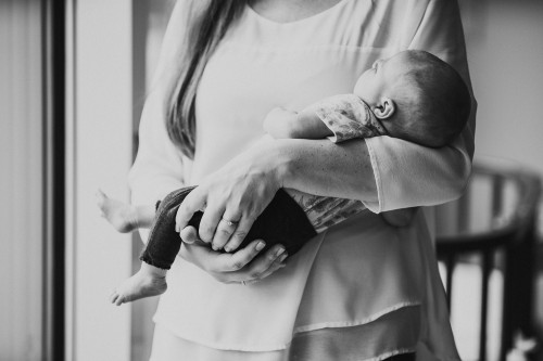 Ein schwarz-weiß Fotos von einer Frau die ein kleines Baby auf dem Arm hält.