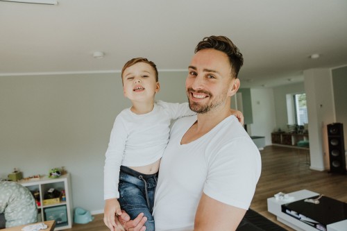 Ein Mann hält einen kleinen Jungen auf dem Arm.