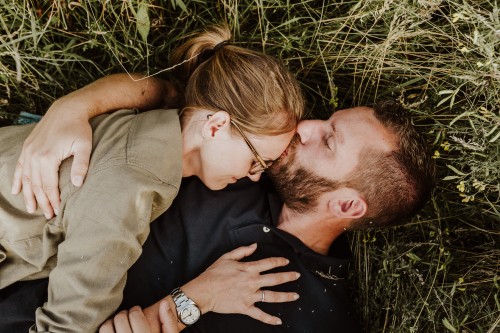 Eine Frau und ein Mann liegen auf einer Wiese und kuscheln.