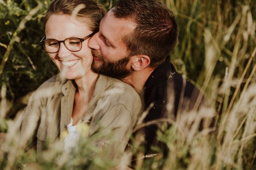 Eine Frau und ein Mann sitzen auf einer Wiese und kuscheln.