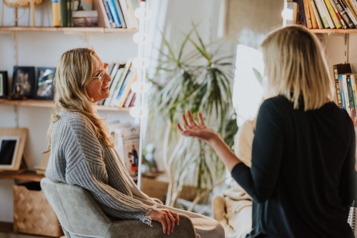 Eine Frau mit Brille unterhält sich mit einer anderen Frau.