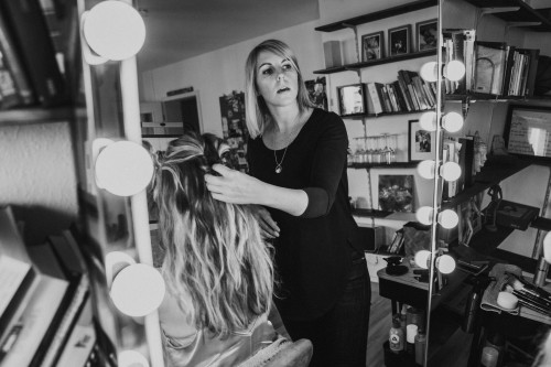 Eine Frau schaut in den Spiegel und richtet einer Frau die Haare.