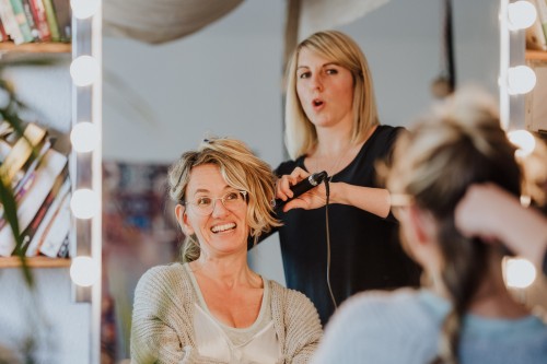 Einer Frau werden von der Stylistin die Haare gemacht.