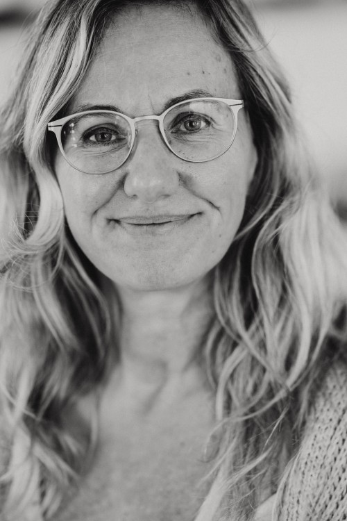 Ein schwarz-weiß Bild von einer lächelnden Frau mit Brille.