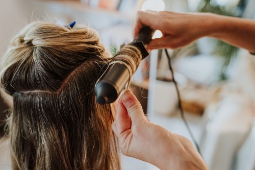 Ein Lockenstab umwickelt mit Haaren.