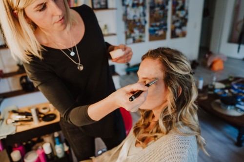 Eine Frau wird von einer Stylistin geschminkt.