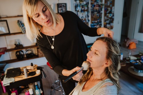 Eine Frau wird von einer Stylistin geschminkt.