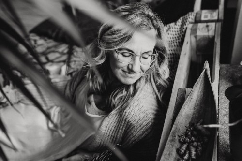 Eine Frau mit Brille, die auf einem Bett sitzt.