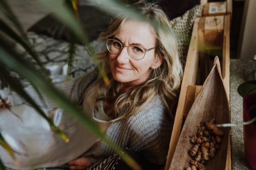 Eine Frau mit Brille, die auf einem Bett sitzt.
