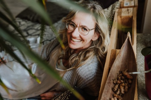 Eine Frau mit Brille, die auf einem Bett sitzt.