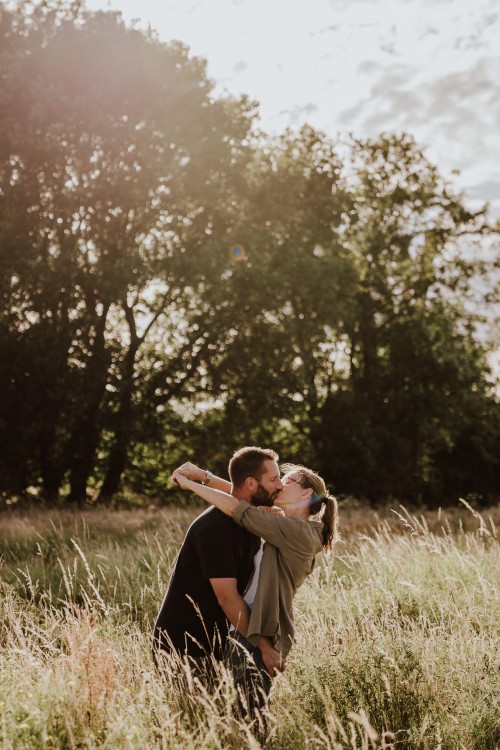 Ein Mann und eine Frau küssen sich mitten auf einer Wiese.