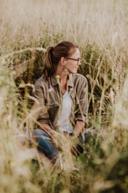 Eine Frau sitzt auf einer Wiese.