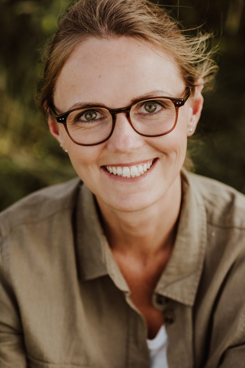 Eine Frau sitzt auf einer Wiese.