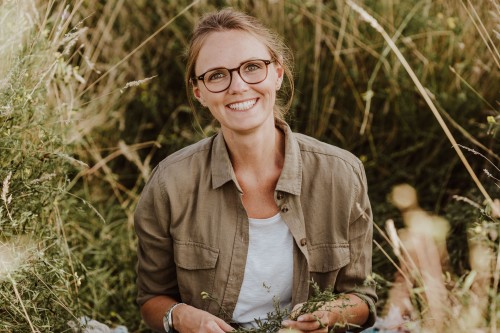 Eine Frau sitzt auf einer Wiese.