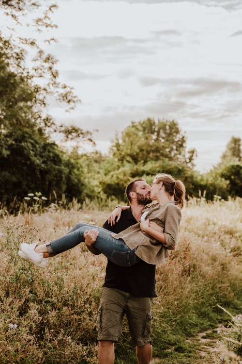 Ein Mann hält eine Frau auf den Händen und küsst sie.