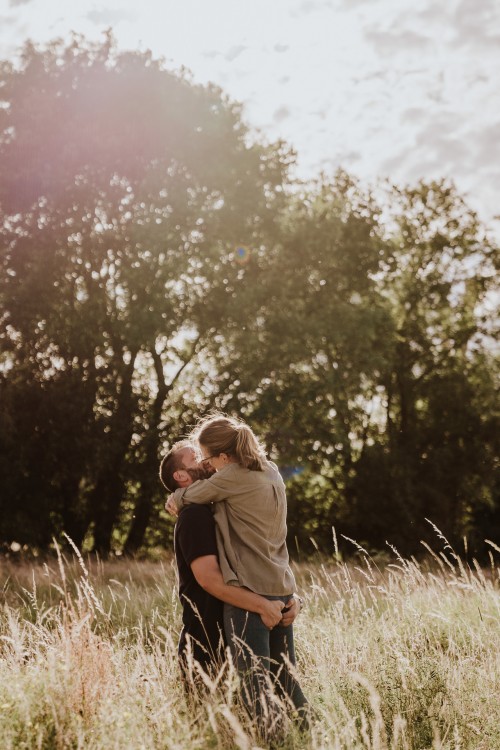 Ein Mann und eine Frau küssen sich auf einer Wiese.