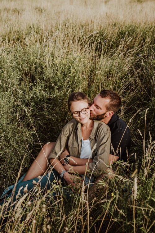 Eine Frau und ein Mann sitzen auf einer Wiese und kuscheln.
