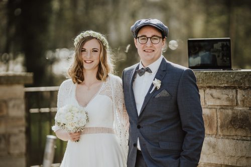 Hochzeitspaar im Vintagestil mit Laptop vor Schloss Borbeck