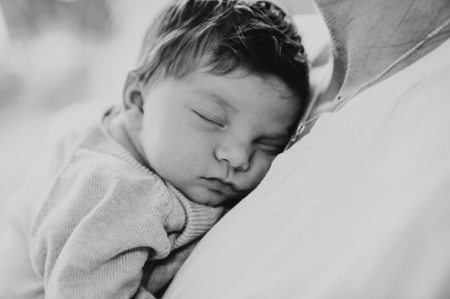 Ein kleines Baby liegt bei einer Frau auf der Brust.