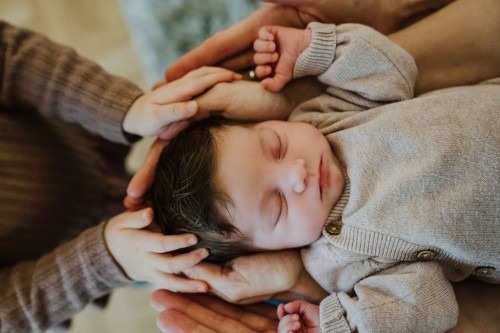 Ein kleines Kind hält seine Hände am Kopf eines kleines Babys.