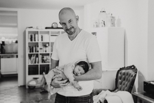 Ein Mann hält ein kleines Baby auf dem Arm.