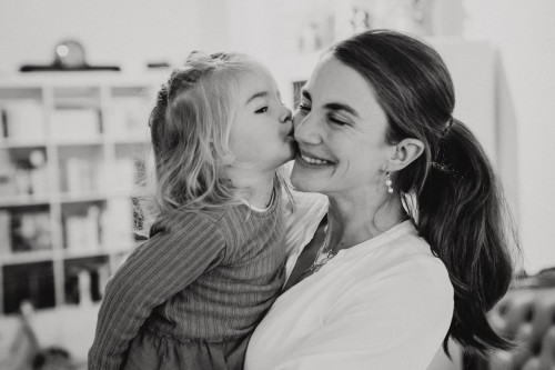 Ein schwarz-weiß Bild von einer Frau die einen Kuss von einem Mädchen bekommt.