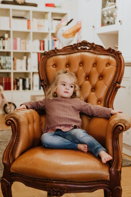 Ein kleines Mädchen sitzt auf einem Sessel.