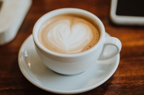 Eine Tasse mit Kaffee und Schaum in Herz Form.