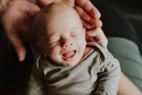 Ein kleines Baby liegt auf den Händen von einem Mann.