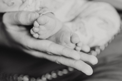 Kleine Babyfüße gehalten von einer großen Hand.