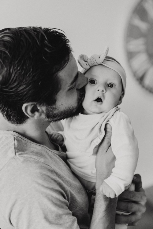 Ein Mann gibt einem Baby einen Kuss auf die Wange.