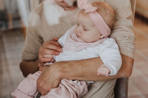 Ein kleines Baby bei einem Mann auf dem Arm.