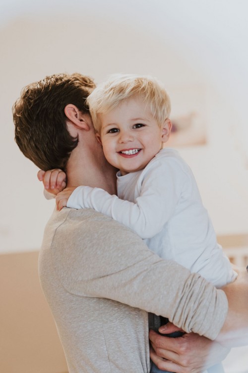 Ein kleiner Junge bei einem Mann auf dem Arm.