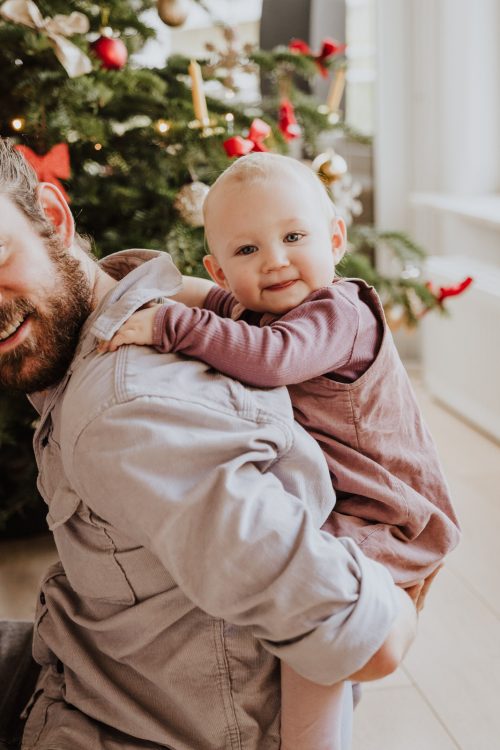 Ein Mann hält ein kleines Baby huckepack.