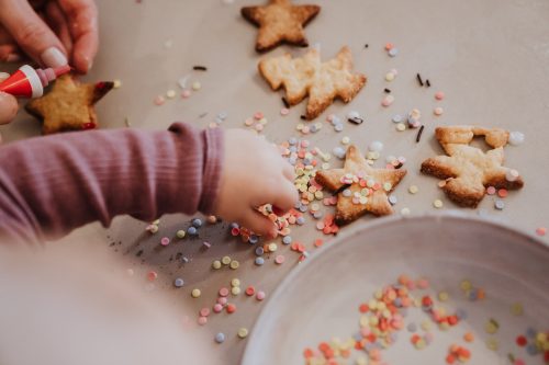Eine Kinderhand und Weihnachtsplätzchen.