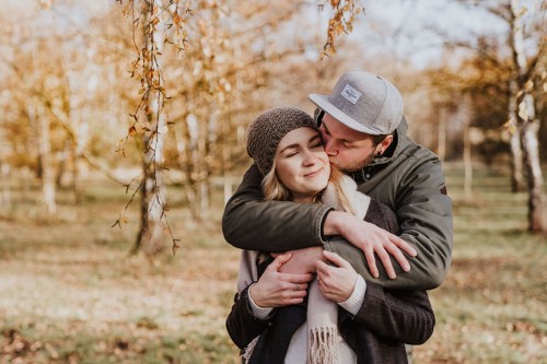 Ein Mann umarmt eine Frau und gibt ihr einen Kuss auf die Wange.