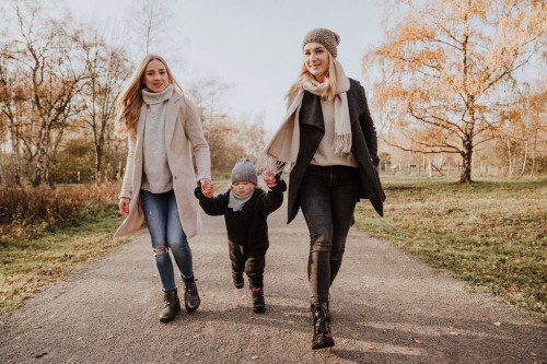 Zwei Frauen spazieren mit einem kleinen Kind durch den Wald.