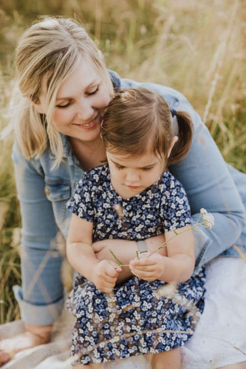Eine Frau und ein kleines Mädchen sitzen auf einer Wiese.