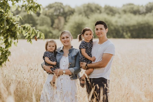 Eine Frau und ein Mann halten zwei kleine Mädchen auf dem Arm.