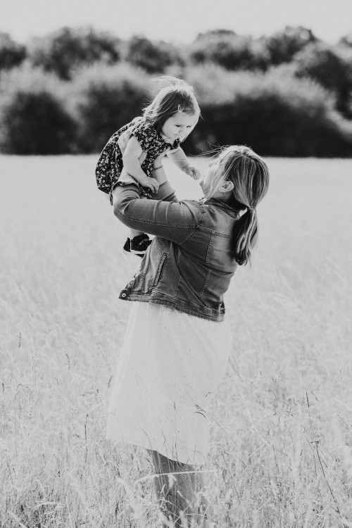 Eine Frau wirft ein kleines Mädchen hoch in die Luft.